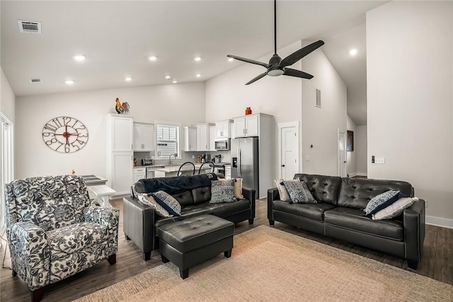living area featuring visible vents, ceiling fan, wood finished floors, and high vaulted ceiling