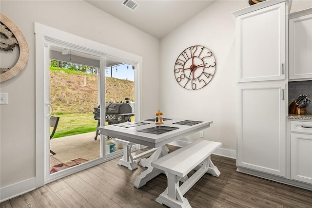 dining space featuring baseboards, visible vents, dark wood finished floors, and vaulted ceiling