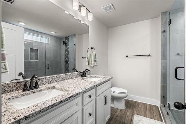 bathroom featuring a sink, a stall shower, wood finished floors, and visible vents