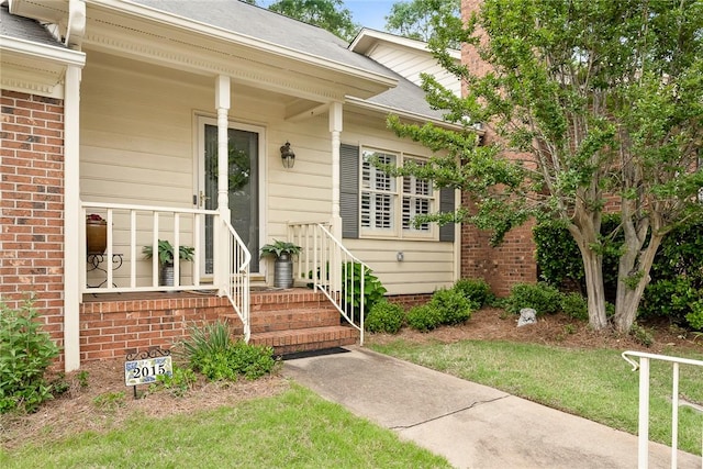 doorway to property with a shingled roof and brick siding