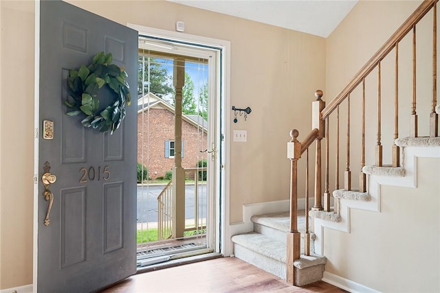 foyer entrance featuring stairs, baseboards, and wood finished floors