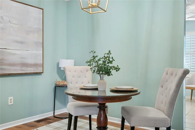 dining room with baseboards, an inviting chandelier, wood finished floors, and visible vents