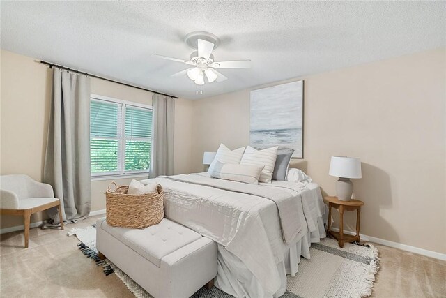 carpeted bedroom featuring a textured ceiling, baseboards, and ceiling fan