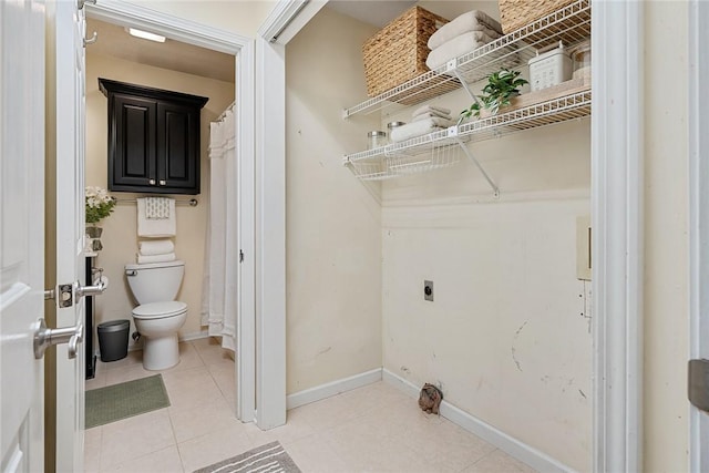 laundry room featuring electric dryer hookup, baseboards, and light tile patterned floors