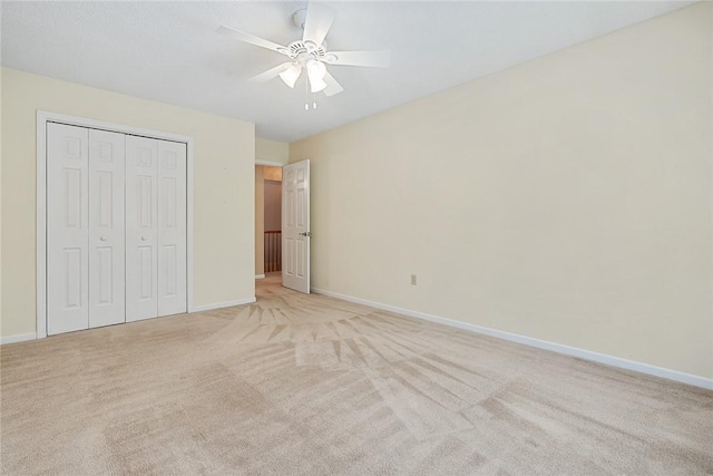 unfurnished bedroom with baseboards, ceiling fan, a closet, and light colored carpet