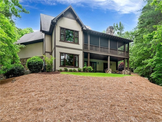 rear view of house featuring a sunroom and a chimney
