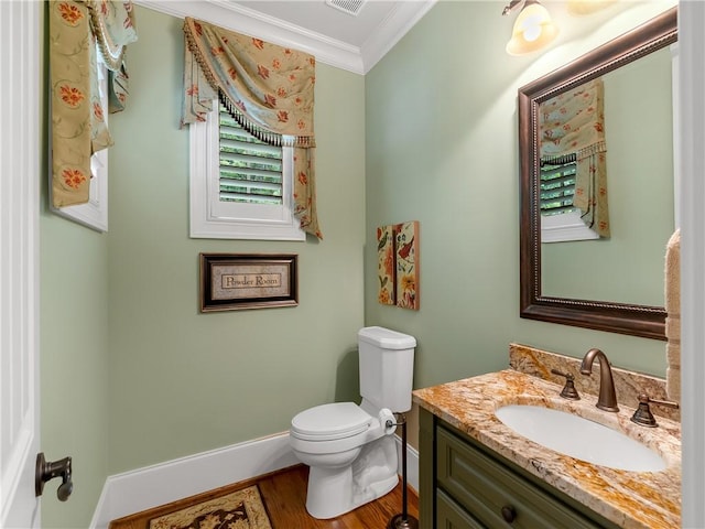 half bathroom with crown molding, wood finished floors, vanity, baseboards, and toilet