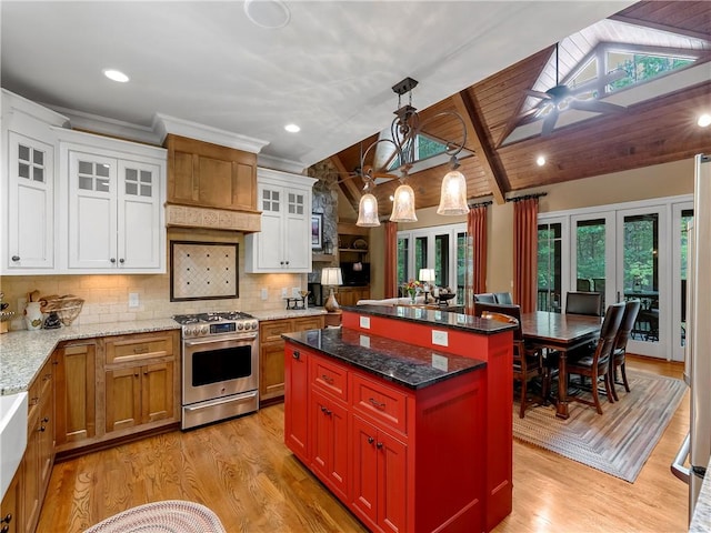 kitchen featuring white cabinets, backsplash, vaulted ceiling with beams, gas range, and a kitchen island