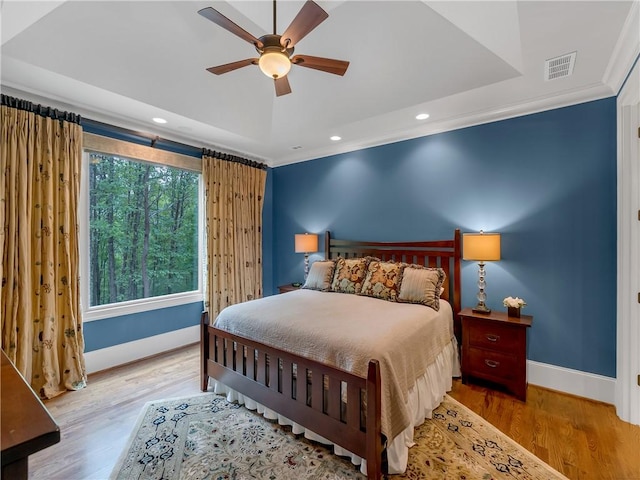 bedroom featuring baseboards, a raised ceiling, wood finished floors, and visible vents