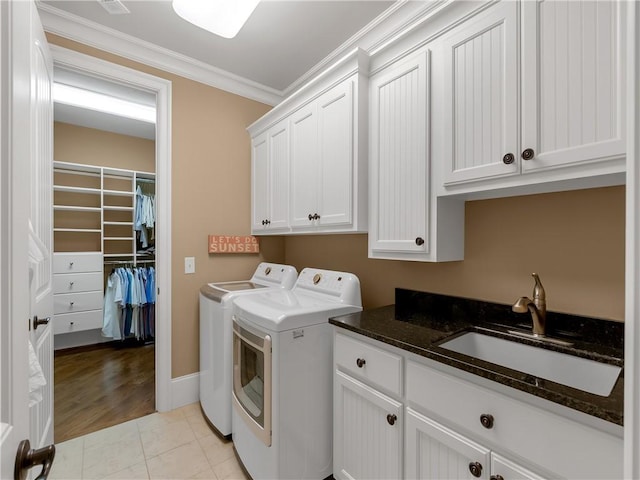 washroom featuring cabinet space, independent washer and dryer, ornamental molding, and a sink
