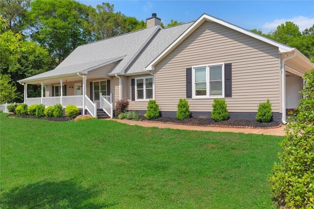 back of house with covered porch, a lawn, and a chimney
