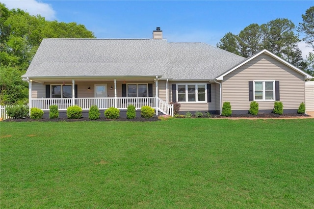 view of front facade with roof with shingles, a chimney, a porch, and a front lawn
