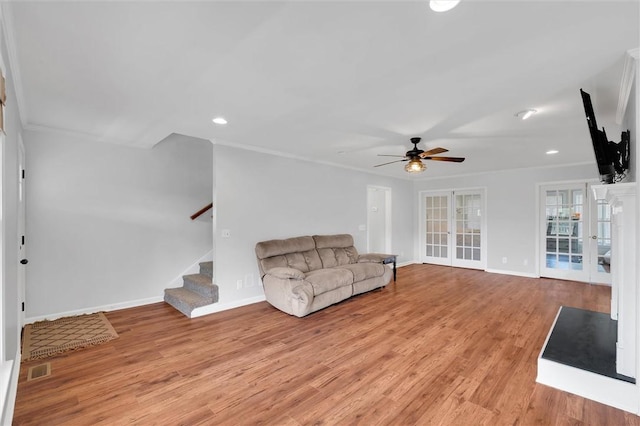 unfurnished living room with baseboards, stairway, french doors, a ceiling fan, and light wood finished floors