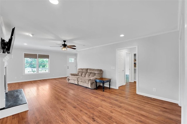 living area featuring light wood-style flooring, a ceiling fan, baseboards, recessed lighting, and ornamental molding