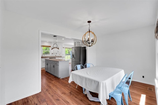 dining space with baseboards, wood finished floors, a chandelier, and visible vents