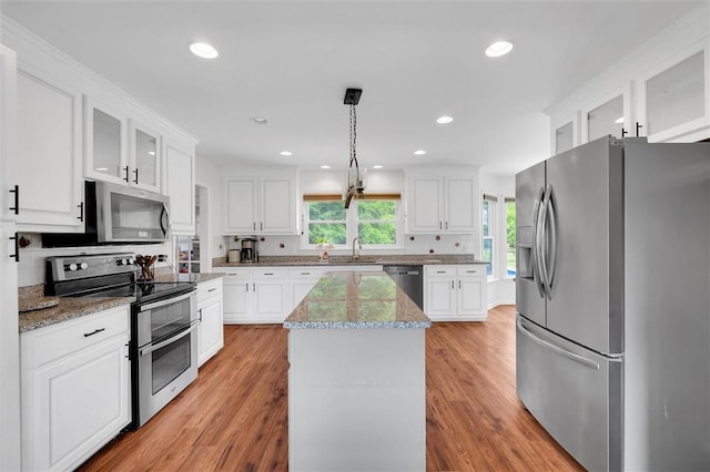 kitchen featuring white cabinets, appliances with stainless steel finishes, a healthy amount of sunlight, and a center island