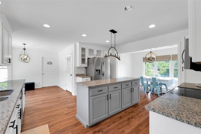 kitchen featuring white cabinets, a chandelier, stainless steel fridge, and wood finished floors