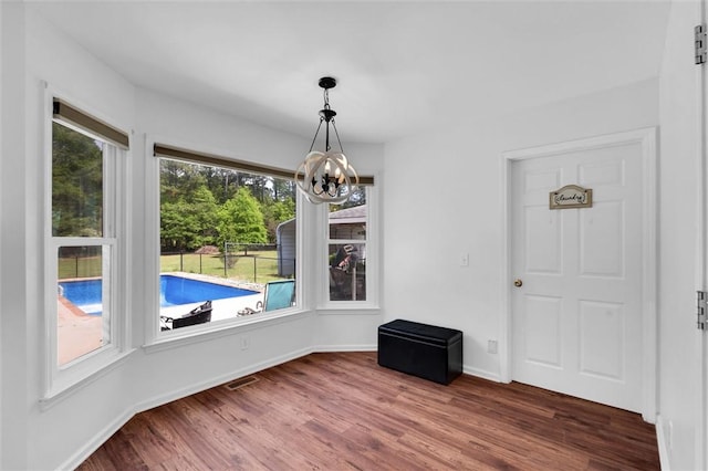 unfurnished dining area with baseboards, wood finished floors, and a notable chandelier