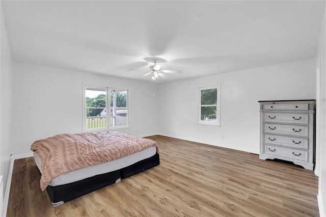 bedroom with baseboards, ceiling fan, wood finished floors, and multiple windows