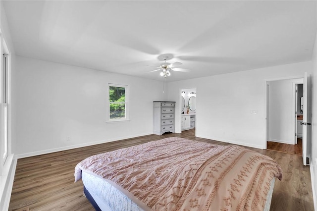 bedroom featuring baseboards, a ceiling fan, ensuite bath, and wood finished floors