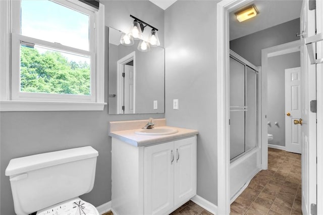 bathroom with vanity, baseboards, bath / shower combo with glass door, and toilet