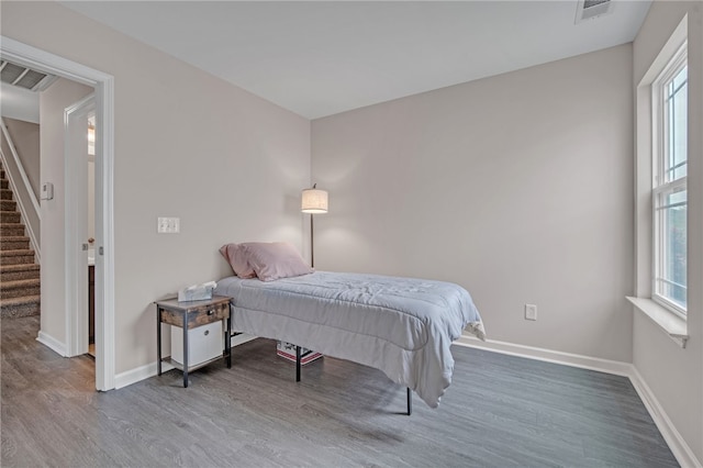 bedroom featuring baseboards, multiple windows, wood finished floors, and visible vents