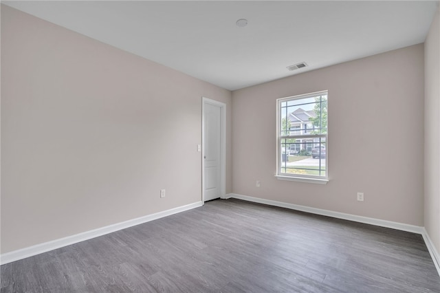 spare room featuring baseboards, dark wood-style flooring, and visible vents