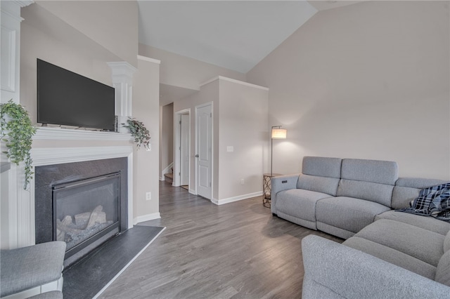 living room with high vaulted ceiling, a glass covered fireplace, baseboards, decorative columns, and wood finished floors