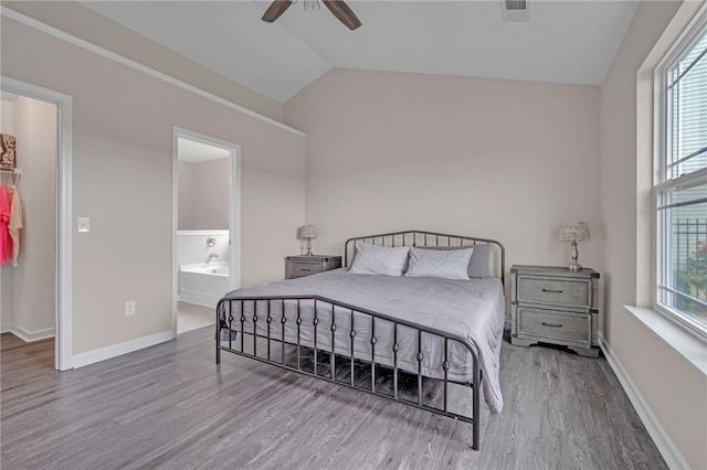 bedroom featuring baseboards, wood finished floors, vaulted ceiling, a spacious closet, and visible vents