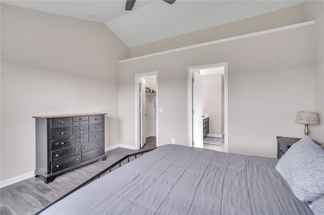 bedroom featuring wood finished floors, baseboards, a spacious closet, a ceiling fan, and vaulted ceiling