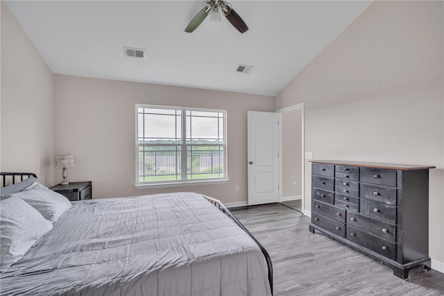 bedroom with ceiling fan, visible vents, wood finished floors, and vaulted ceiling