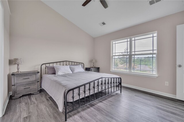 bedroom featuring visible vents, baseboards, wood finished floors, and vaulted ceiling