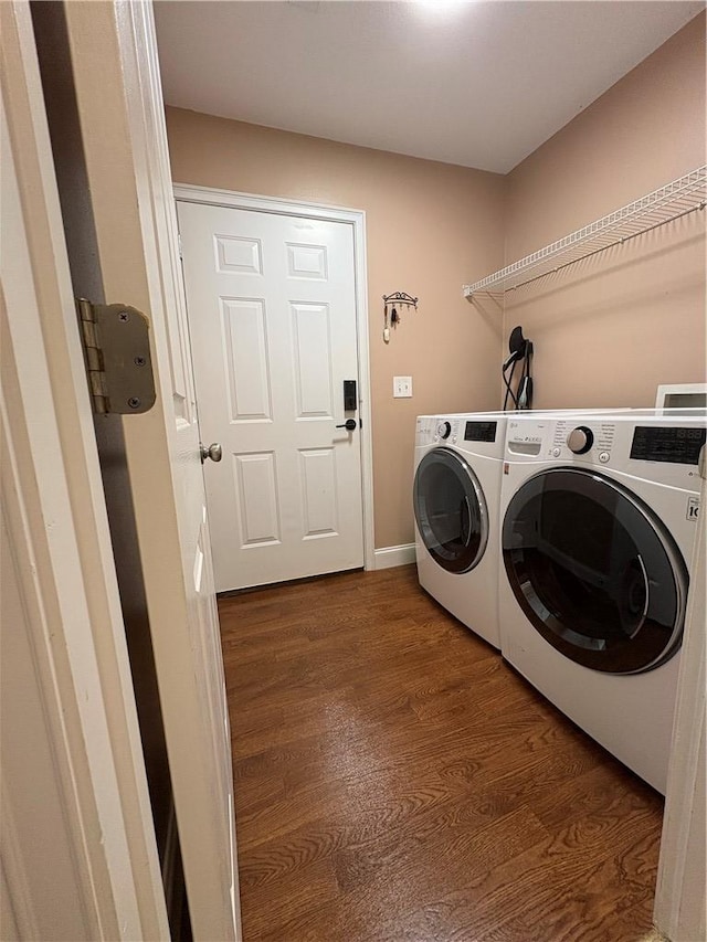 clothes washing area featuring laundry area, baseboards, dark wood-style flooring, and washing machine and dryer