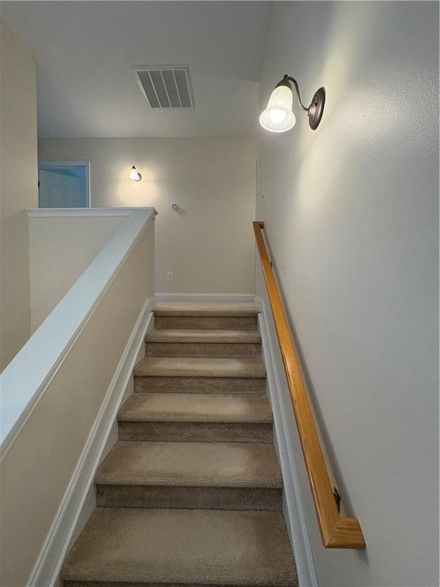 stairway with baseboards, visible vents, and carpet