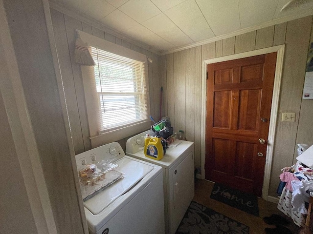laundry area with crown molding, laundry area, wood walls, and washer and clothes dryer