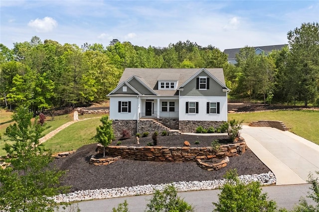 view of front facade featuring board and batten siding, driveway, and a front yard
