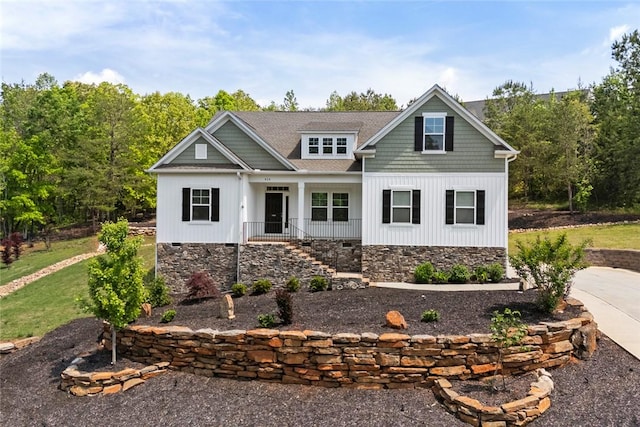 craftsman house with roof with shingles, board and batten siding, a porch, and stone siding