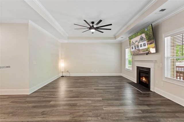 unfurnished living room with ceiling fan, visible vents, dark wood-style floors, a glass covered fireplace, and a tray ceiling