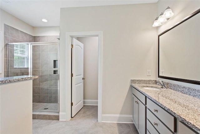 bathroom with vanity, tile patterned flooring, baseboards, and a shower stall