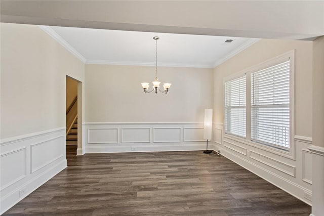 unfurnished dining area featuring ornamental molding, a wainscoted wall, a notable chandelier, and dark wood-style floors