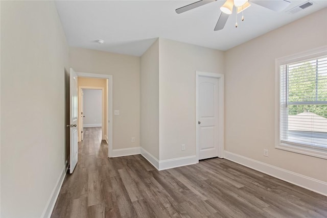 unfurnished room with ceiling fan, visible vents, dark wood-style floors, and baseboards