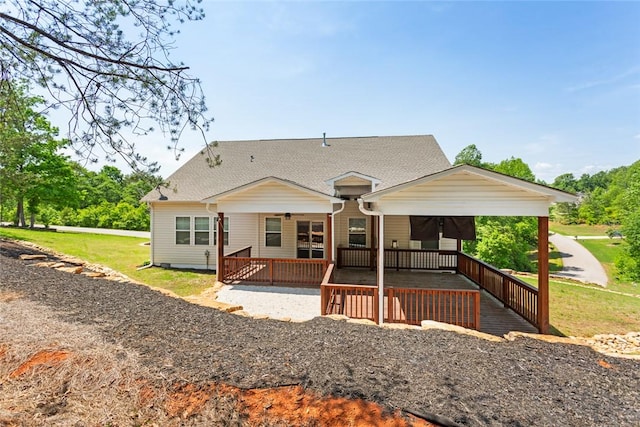 rear view of house featuring ceiling fan, roof with shingles, and a yard