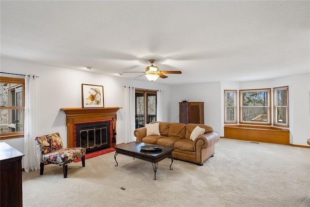 carpeted living area with ceiling fan, a fireplace with flush hearth, and plenty of natural light