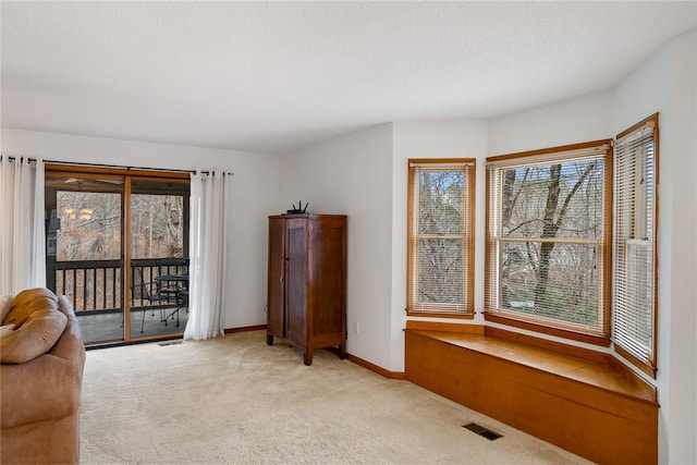 living area with visible vents, baseboards, and light carpet