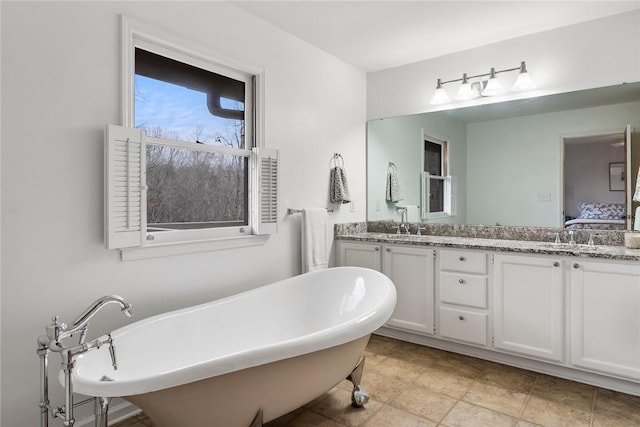 ensuite bathroom featuring double vanity, a freestanding tub, and ensuite bath