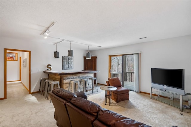 living area featuring visible vents, baseboards, light colored carpet, a textured ceiling, and rail lighting