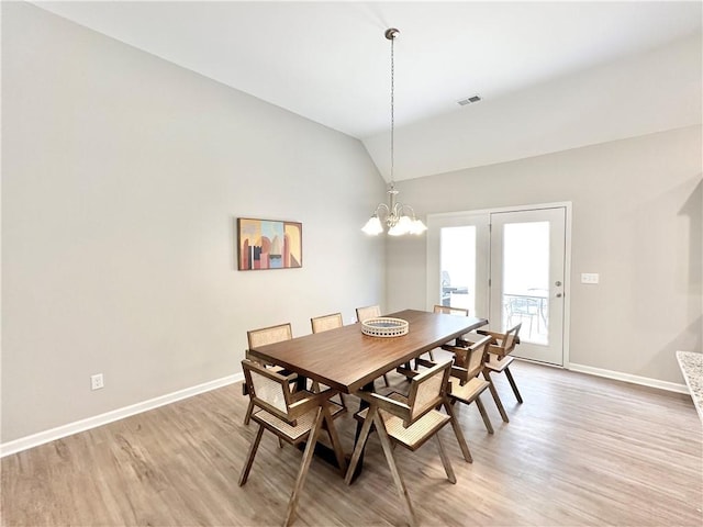 dining room featuring visible vents, baseboards, a notable chandelier, light wood-style floors, and lofted ceiling