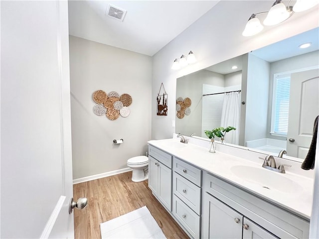 full bath with a sink, double vanity, wood finished floors, and visible vents