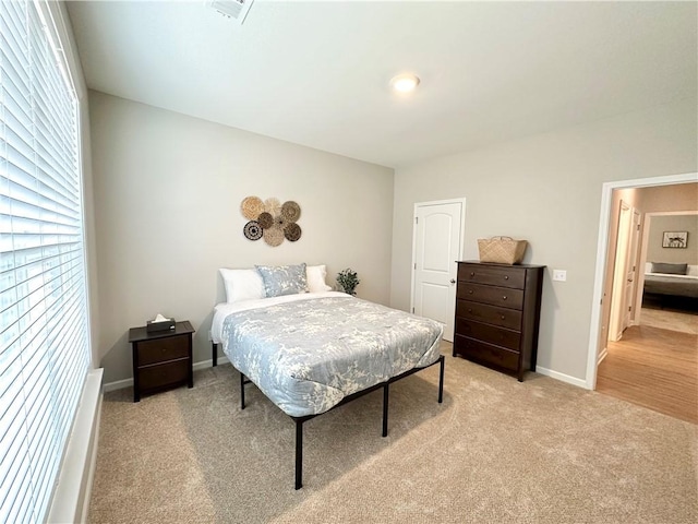 bedroom with baseboards and light carpet