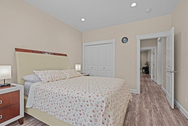 bedroom with baseboards, recessed lighting, wood finished floors, and a closet
